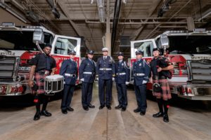 A photo of seven Huntsville Fire & Rescue team members in front of two fire trucks