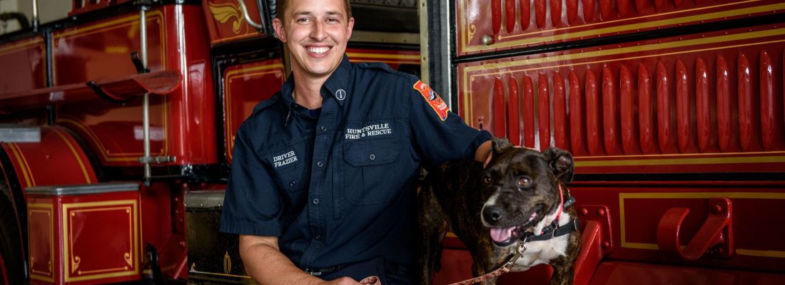 Photo of a Huntsville Fire and Rescue team member next to vintage fire truck